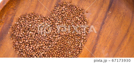 Theme of diet and weight loss on a white background. buckwheat in a wooden plate is laid out in the shape of a heart. 67173930