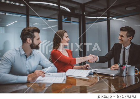 Happy couple making an agreement with a sales agent 67174242