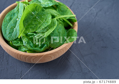 Fresh spinach leaves in wooden bowl on dark 67174889