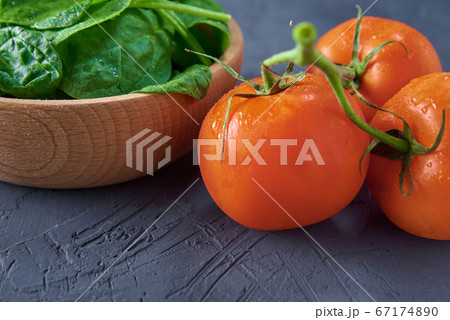 Fresh spinach leaves in wooden bowl and tomato on 67174890