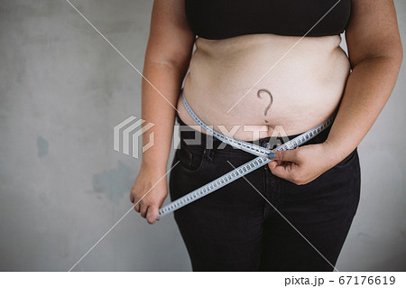 Overweight woman measuring waist with measure tape Overweight woman measuring waist with measure tape 67176619