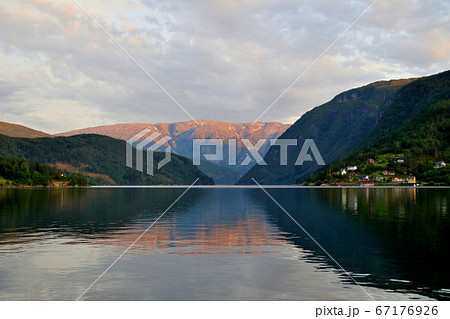 ノルウェー　ハダンゲルフィヨルド、ウルヴィク地区ホテルより南側の黄昏迫るのどかな水面と夕日の山を望む 67176926