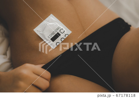 Condom lying on woman body for sexual protection 67178118