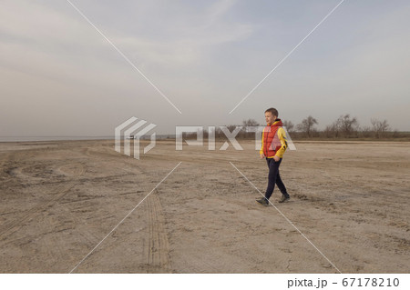 A boy of 10 years old plays soccer on an empty beach. 67178210