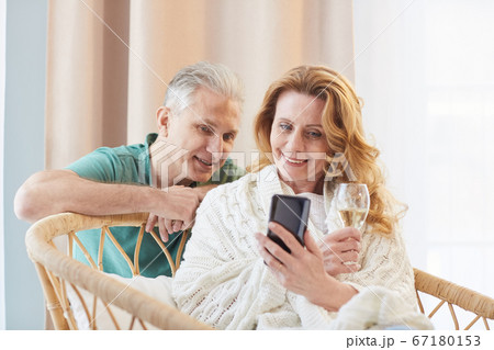 Portrait of Elegant Mature Couple Looking at Smartphone Screen at Home Portrait of Elegant Mature Couple Looking at Smartphone Screen at Home 67180153