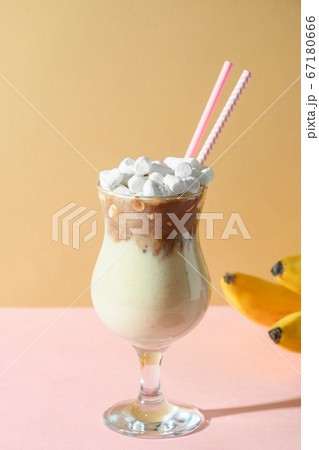 Banana milkshake on colorful pink and beige paper. Banana milkshake on colorful pink and beige paper. 67180666