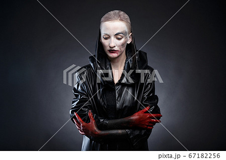 Picture of woman in black leather raincoat with red hands 67182256
