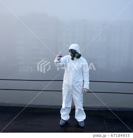 Worker scientist wearing protective coverall and gas mask doing ecological tests on the roof 67184933