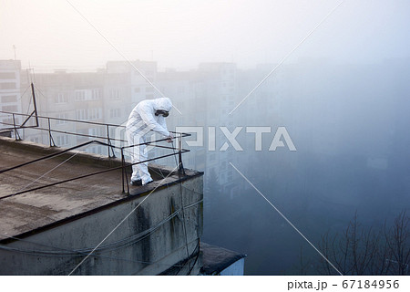 Worker scientist wearing protective coverall and gas mask doing ecological tests on the roof Worker scientist wearing protective coverall and gas mask doing ecological tests on the roof 67184956