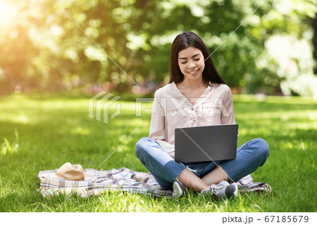 Freelance Concept. Smiling Asian Girl Working On Laptop Outdoors, Sitting On Lawn 67185679
