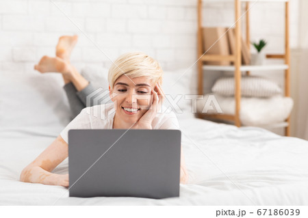 Mature lady with vitiligo browsing on laptop in bed Mature lady with vitiligo browsing on laptop in bed 67186039