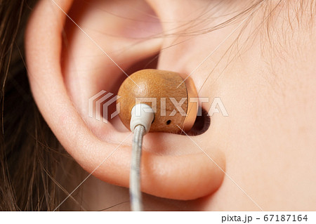 Wooden earphone inserted in the ear of a teenage girl close up Wooden earphone inserted in the ear of a teenage girl close up 67187164