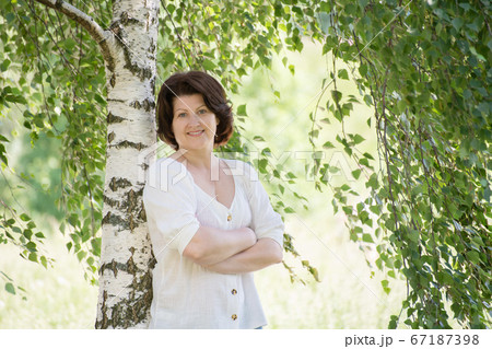 Russian woman near the birch in the summer Russian woman near the birch in the summer 67187398
