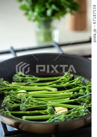 Cooking broccolini in a fried pan. Cooking broccolini in a fried pan. 67187538