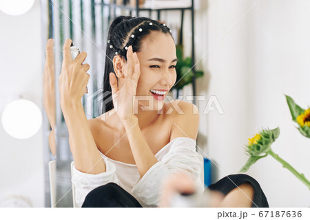 Woman applying hair spray Woman applying hair spray 67187636