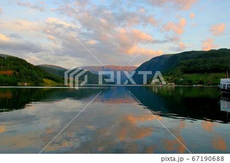 ノルウェー　ハダンゲルフィヨルド、ウルヴィク地区ホテル南側より白夜の黄昏の水面と夕焼け空と山々を望む 67190688