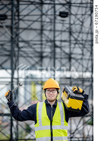 Male Asian mechanic carrying work tool at site 67190754
