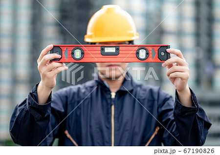 Worker man holding red aluminium spirit level tool 67190826