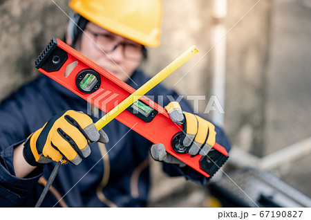 Worker man holding level tool and tape measure 67190827