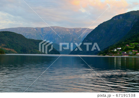 ノルウェー　ハダンゲルフィヨルド、ウルヴィク地区、白夜の黄昏の水面と山と空の変化の推移を楽しむアップ 67191538