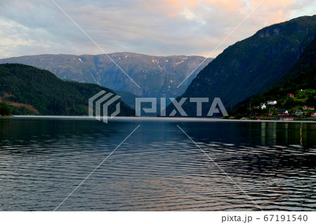 ノルウェー　ハダンゲルフィヨルド、ウルヴィク地区、白夜の黄昏の山と水面と空の変化の推移を楽しむアップ 67191540