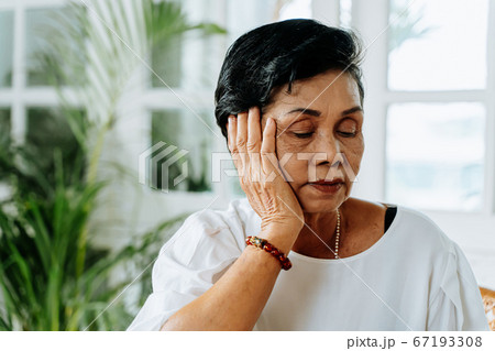 Stressed senior Asian female leaning on hand and pondering about problems at home. Elderly woman thinking about something Stressed senior Asian female leaning on hand and pondering about problems at home. Elderly woman thinking about something 67193308