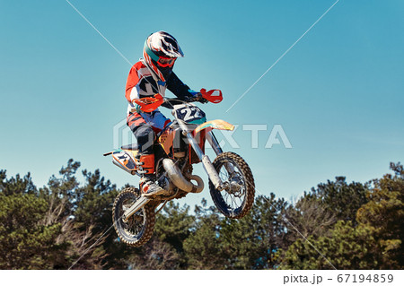 Extreme concept, challenge yourself. Extreme jump on a motorcycle on a background of blue sky with clouds. Copy space, all or nothing. 67194859