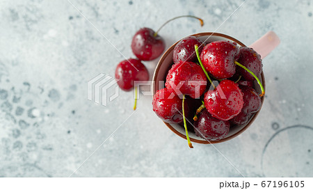 pink mugs with fresh ripe cherries. 67196105