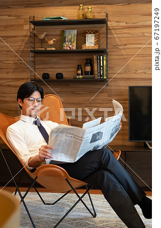リビングで新聞を読む若いビジネスマン リビングで新聞を読む若いビジネスマン 67197249