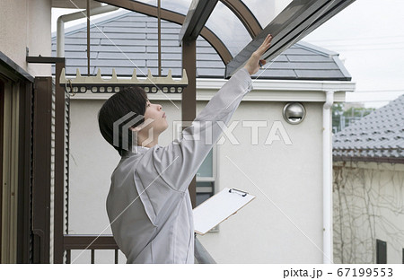住宅　バルコニーのサンルーフを調査するビジネスマン 67199553