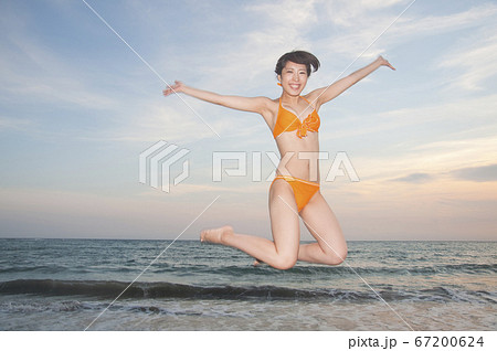 海でジャンプする水着女性の写真素材