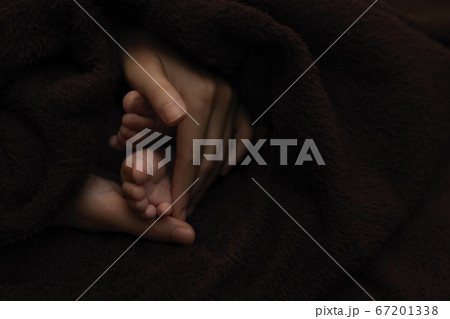Mother hands  holding newborn baby feet, dark 67201338