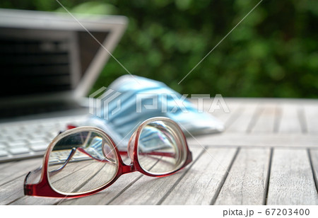 Work at home. Medical face mask on top of computer Work at home. Medical face mask on top of computer 67203400