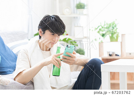 お風呂上りにビールを飲みながらスマホを見る若い男性 お風呂上りにビールを飲みながらスマホを見る若い男性 67203762