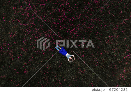 Woman lying on green grass in park 67204282