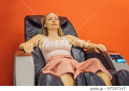 Beautiful young woman relaxing on the massage chair in airport or in the mall 67207147