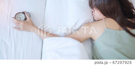 alarm clock and asian woman hand stop time in bed 67207928
