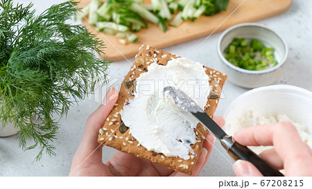 Speading cream cheese on rye crispbread 67208215