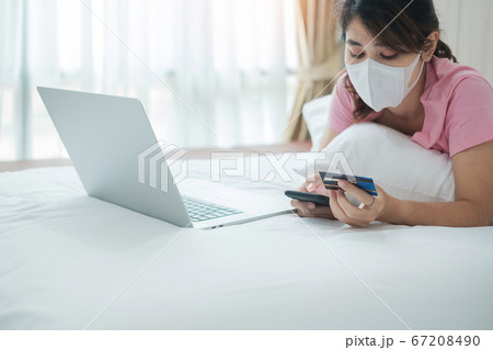 woman with face mask holding credit card and using 67208490