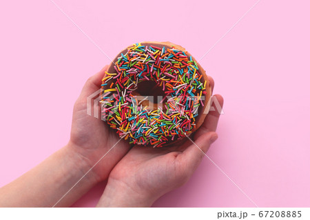 Chocolate donut on pink background in hand. Chocolate donut on pink background in hand. 67208885