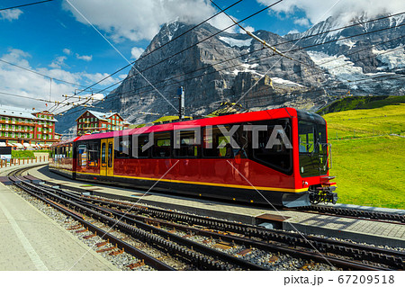 Train station with mountains and modern tourist train, Grindelwald, Switzerland  67209518