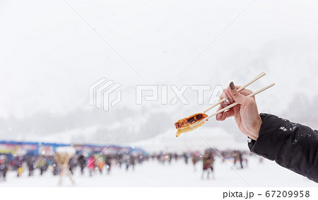 hand holding chopsticks with grilled squid in snow hand holding chopsticks with grilled squid in snow 67209958