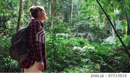 Young woman in a plaid shirt and with a backpack in a rainforest Young woman in a plaid shirt and with a backpack in a rainforest 67214010