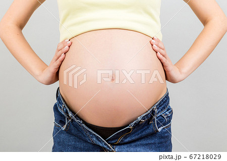 Cropped image of pregnant woman in unzipped jeans Cropped image of pregnant woman in unzipped jeans 67218029