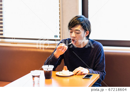 カフェでケーキを食べる若い男性の写真素材