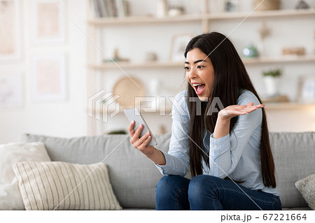 Unexpected Message. Asian girl holding smartphone at home, emotionally reacting to news 67221664