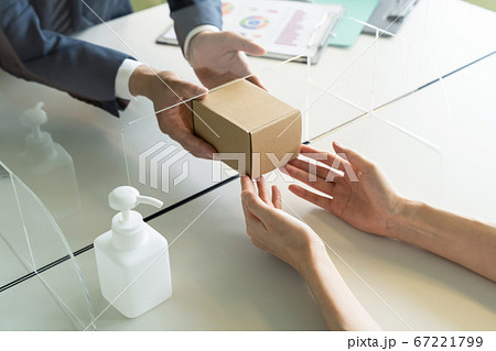 アクリルパーティション越しに荷物を受け渡す人々　感染対策　ソーシャルディスタンス 67221799