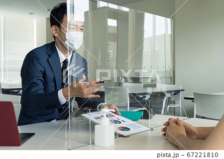 アクリルパーティション越しに話すビジネスマン　感染対策　ソーシャルディスタンス 67221810