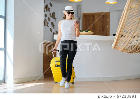 Adult woman with luggage with suitcase going to the hotel lobby 67223891