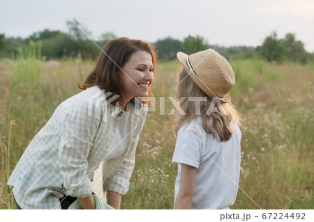 Smiling mother talking with child daughter, summer nature 67224492